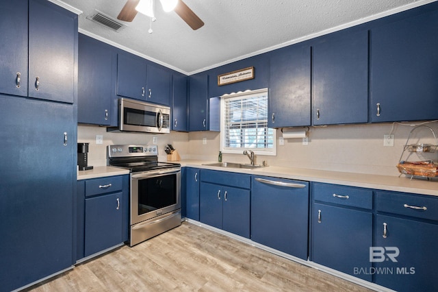 kitchen with appliances with stainless steel finishes, sink, ornamental molding, blue cabinetry, and light wood-type flooring