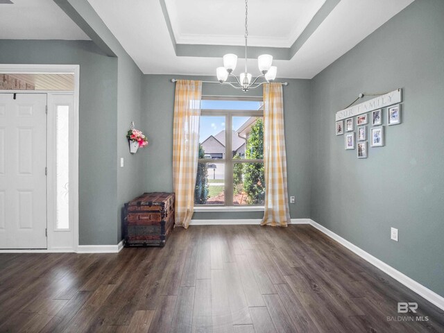 17163 Feder Dr, Foley, AL 36535 - unfurnished dining area with a tray ceiling, baseboards, an inviting chandelier, and dark wood-style flooring