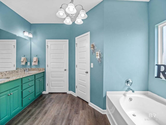 17163 Feder Dr, Foley, AL 36535 - bathroom featuring a garden tub, a chandelier, wood finished floors, baseboards, and double vanity