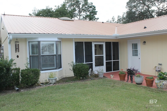 rear view of property featuring a lawn and a sunroom