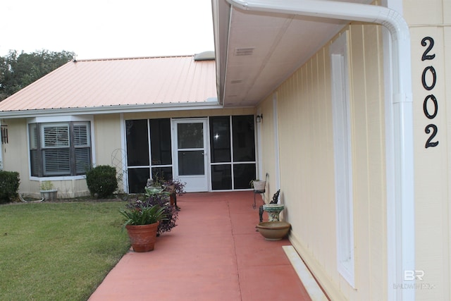 rear view of property featuring a lawn, a patio area, and a sunroom