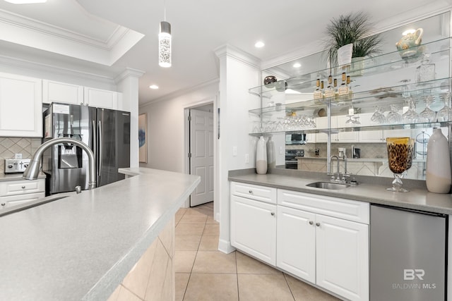 kitchen with a sink, appliances with stainless steel finishes, ornamental molding, and decorative backsplash