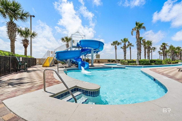 community pool with a water slide, a hot tub, and a patio area