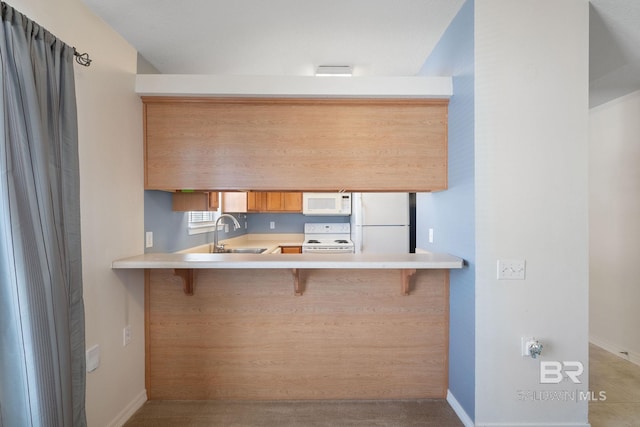 kitchen with kitchen peninsula, white appliances, a breakfast bar, and sink