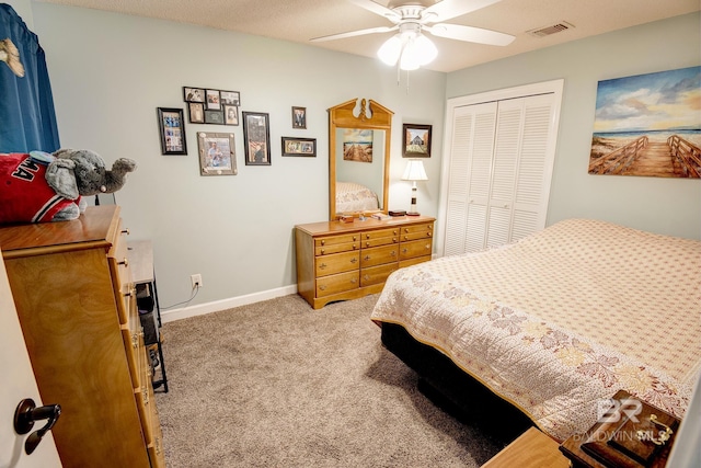 bedroom with ceiling fan, a closet, light colored carpet, and a textured ceiling