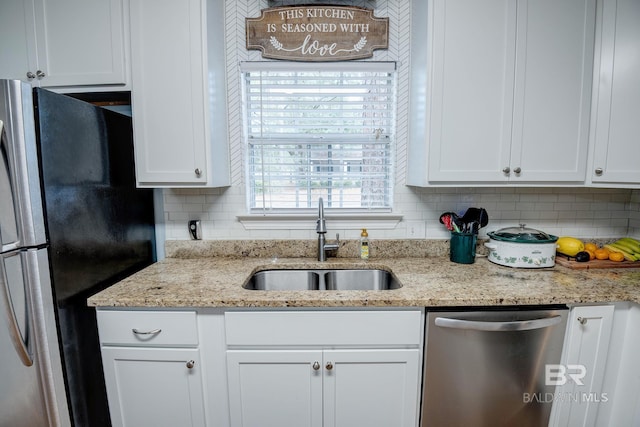 kitchen featuring tasteful backsplash, light stone counters, stainless steel appliances, sink, and white cabinets