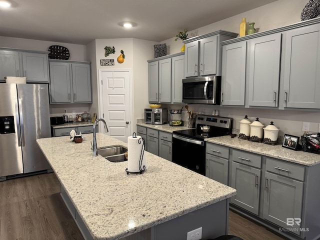 kitchen featuring sink, light stone counters, a kitchen island with sink, and stainless steel appliances