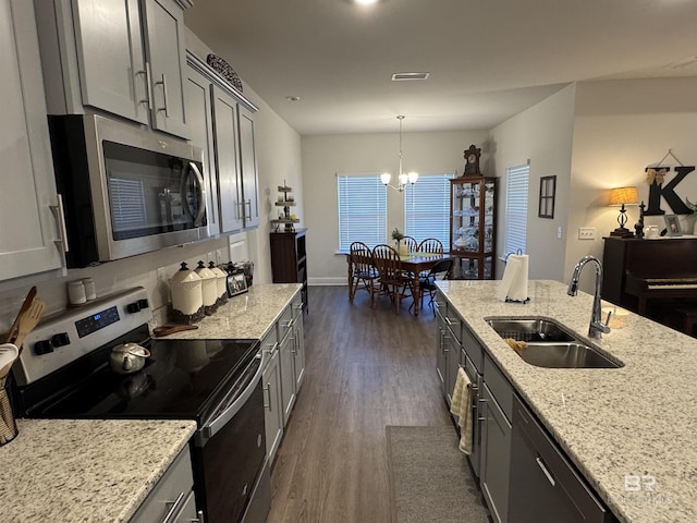 kitchen with hanging light fixtures, appliances with stainless steel finishes, sink, gray cabinetry, and light stone counters