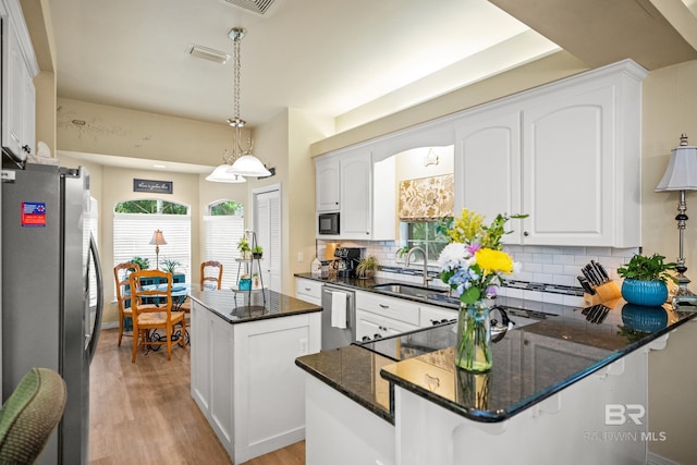 11346 County Road 99, Lillian, AL 36549 - kitchen with stainless steel appliances, a sink, light wood-type flooring, a kitchen island, and decorative backsplash