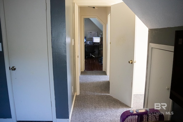 hall with vaulted ceiling, carpet, and a textured ceiling