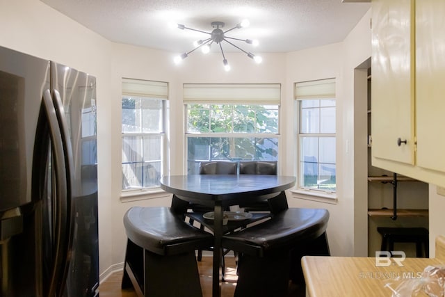 dining area with a textured ceiling, hardwood / wood-style flooring, and a chandelier