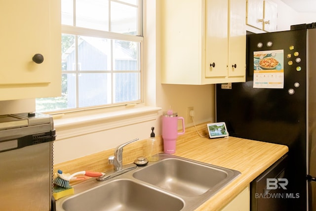 kitchen with sink, white cabinets, and stainless steel refrigerator