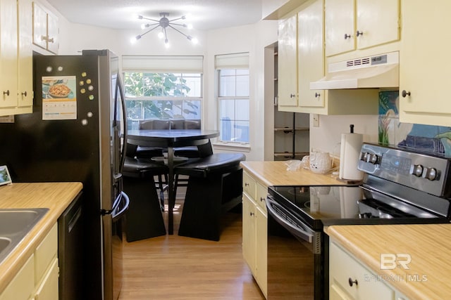 kitchen featuring appliances with stainless steel finishes, a chandelier, and light wood-type flooring