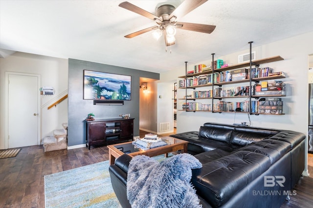 living room featuring ceiling fan, a textured ceiling, and dark hardwood / wood-style floors