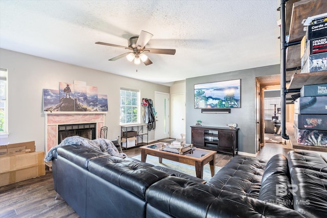 living room with a premium fireplace, a textured ceiling, wood-type flooring, and ceiling fan