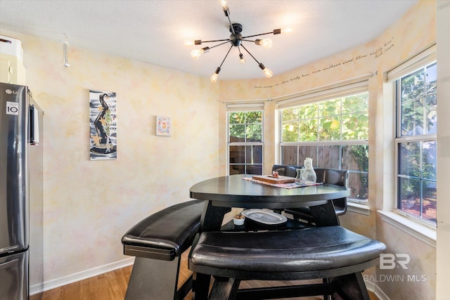 dining space with hardwood / wood-style floors, a textured ceiling, an inviting chandelier, and plenty of natural light