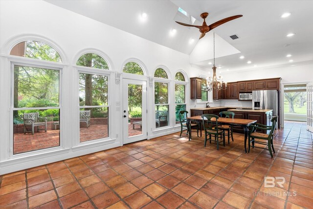 tiled dining space featuring ceiling fan with notable chandelier, sink, and high vaulted ceiling