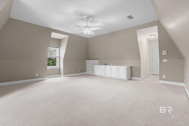 additional living space featuring light carpet, lofted ceiling, and ceiling fan