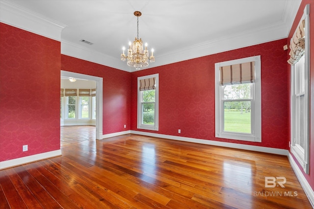 empty room featuring crown molding, a chandelier, and hardwood / wood-style flooring