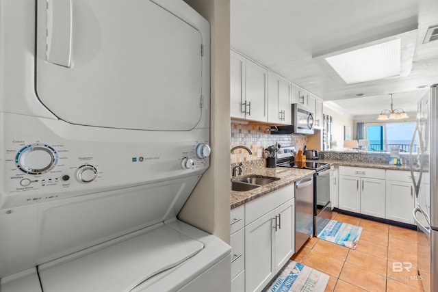 laundry area featuring a sink, stacked washing maching and dryer, light tile patterned floors, laundry area, and visible vents