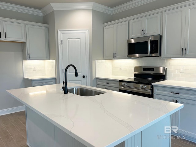 kitchen with a center island with sink, stainless steel appliances, light stone countertops, ornamental molding, and sink