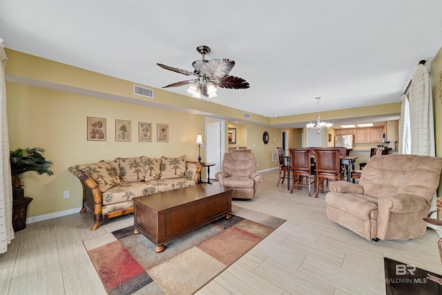 living room featuring baseboards, visible vents, and ceiling fan with notable chandelier