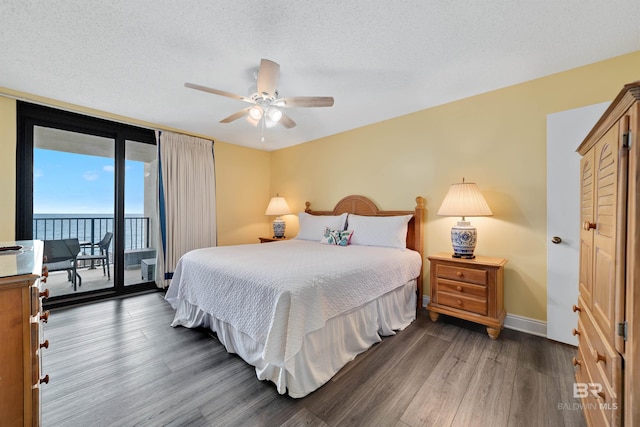 bedroom with a ceiling fan, a textured ceiling, baseboards, wood finished floors, and access to exterior