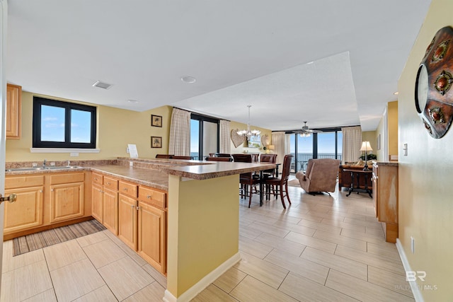 kitchen with a peninsula, visible vents, a healthy amount of sunlight, and light brown cabinetry