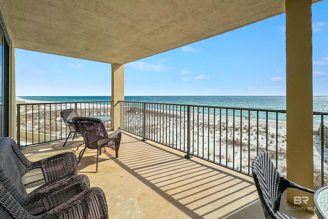 balcony with a water view and a view of the beach
