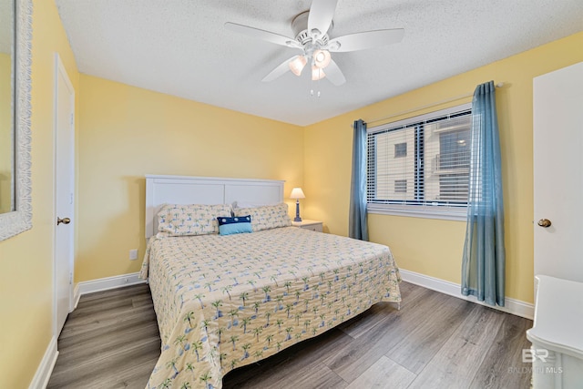 bedroom featuring baseboards, a textured ceiling, a ceiling fan, and wood finished floors