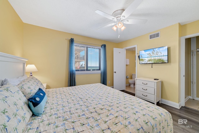 bedroom with connected bathroom, wood finished floors, visible vents, baseboards, and ceiling fan