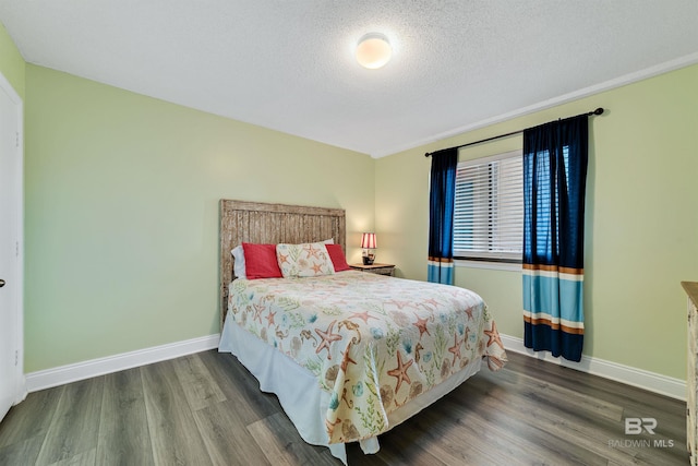 bedroom with a textured ceiling, baseboards, and wood finished floors