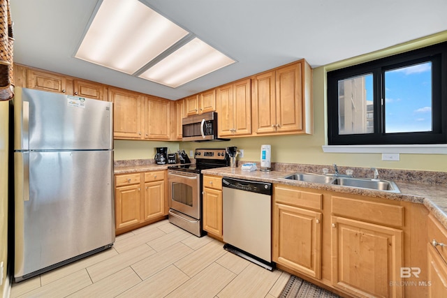 kitchen with light countertops, stainless steel appliances, light brown cabinets, and a sink