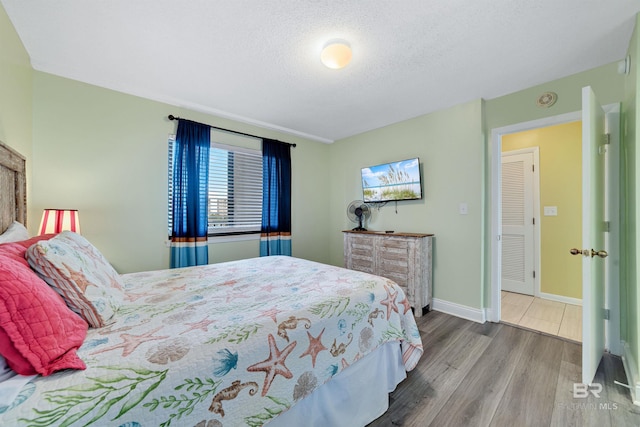bedroom with baseboards, a textured ceiling, and wood finished floors