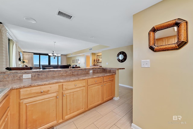 kitchen with baseboards, light brown cabinetry, an inviting chandelier, and visible vents