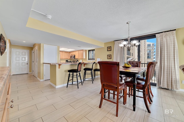 dining area featuring a chandelier, a textured ceiling, and baseboards
