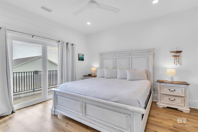 bedroom featuring access to exterior, light hardwood / wood-style floors, ceiling fan, and wood walls