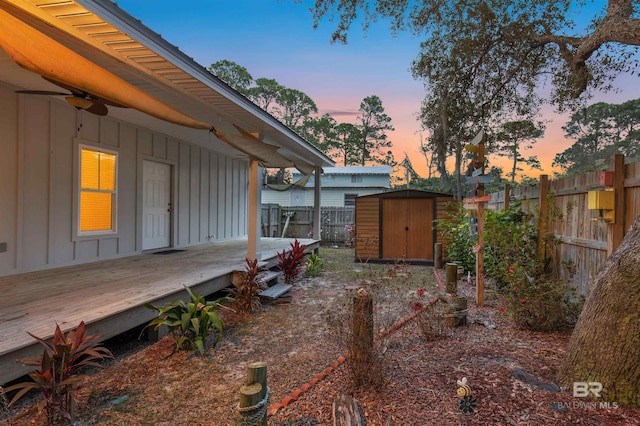 yard at dusk featuring a storage unit and a wooden deck