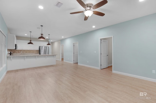 unfurnished living room featuring ceiling fan and light wood-type flooring