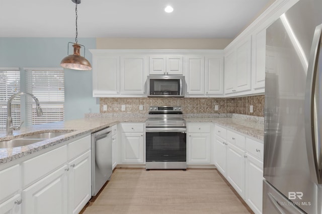 kitchen featuring white cabinets, appliances with stainless steel finishes, pendant lighting, and sink