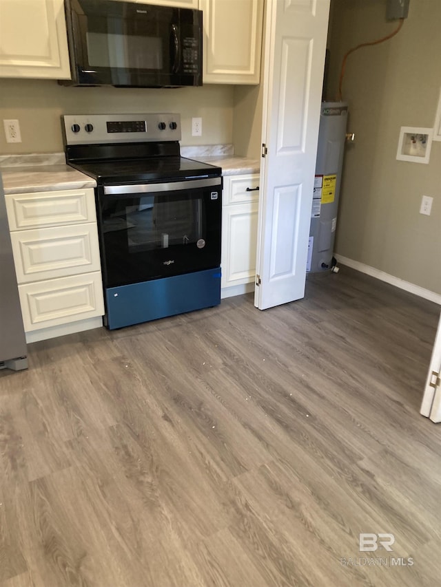 kitchen featuring light countertops, black microwave, light wood-style flooring, electric range, and electric water heater