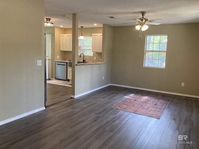 unfurnished living room with visible vents, a ceiling fan, a sink, dark wood-type flooring, and baseboards