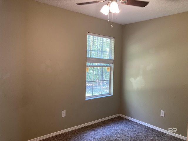 spare room featuring dark colored carpet, a healthy amount of sunlight, baseboards, and ceiling fan