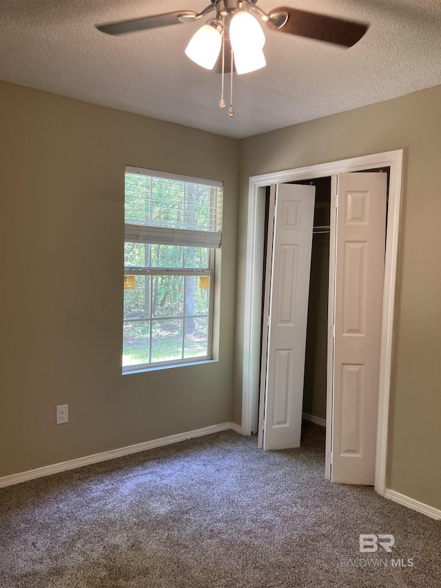 unfurnished bedroom featuring carpet floors, a textured ceiling, and baseboards