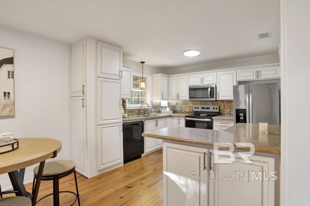 kitchen with hanging light fixtures, white cabinets, stainless steel appliances, and sink