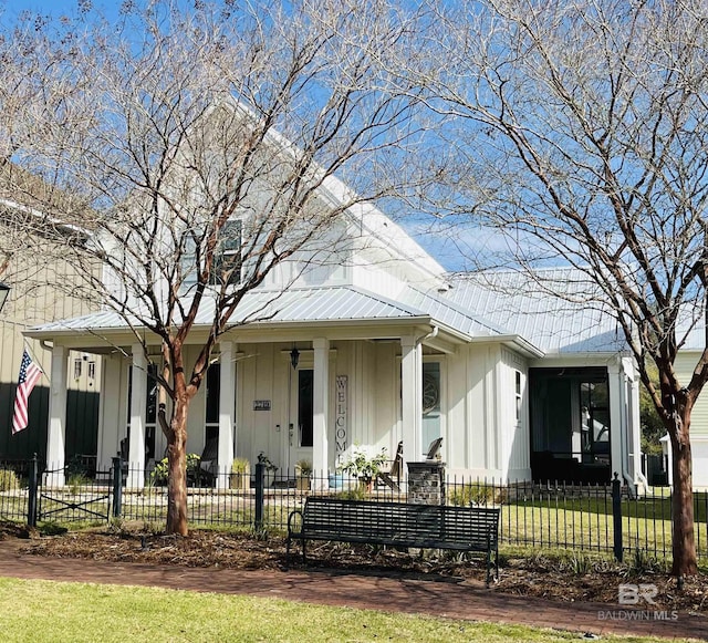 view of front facade with metal roof, a porch, a fenced front yard, and board and batten siding