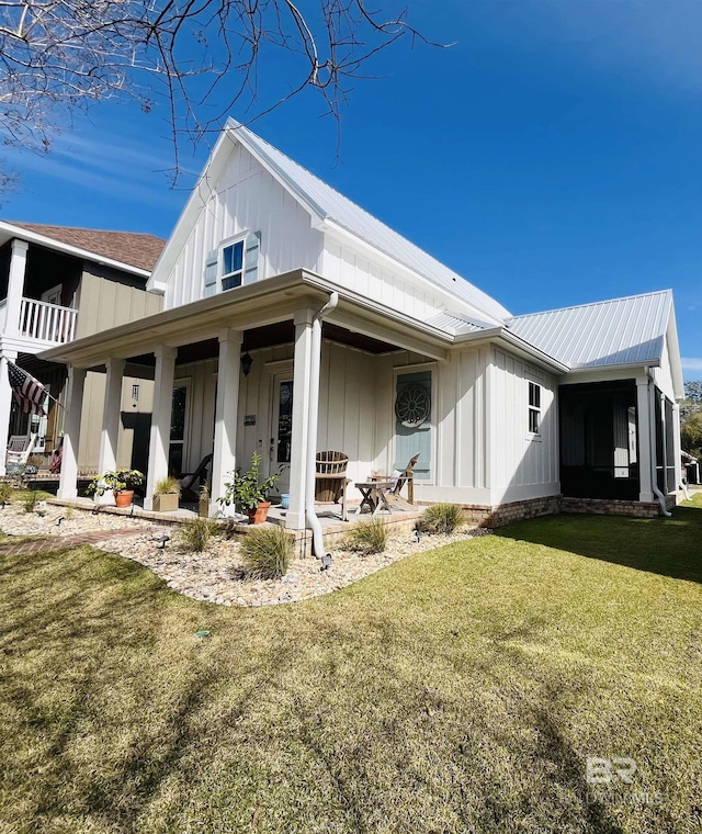 view of home's exterior featuring board and batten siding, metal roof, a lawn, and a patio