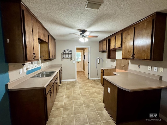 43265 Jones Rd, Bay Minette, AL 36507 - kitchen with ceiling fan, light countertops, a textured ceiling, a peninsula, and dark brown cabinetry