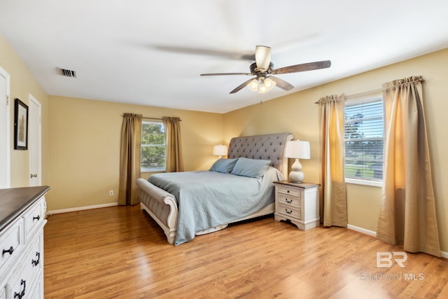 bedroom featuring light wood-style floors, visible vents, baseboards, and ceiling fan