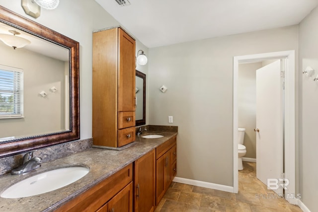 full bathroom featuring baseboards, a sink, double vanity, and toilet